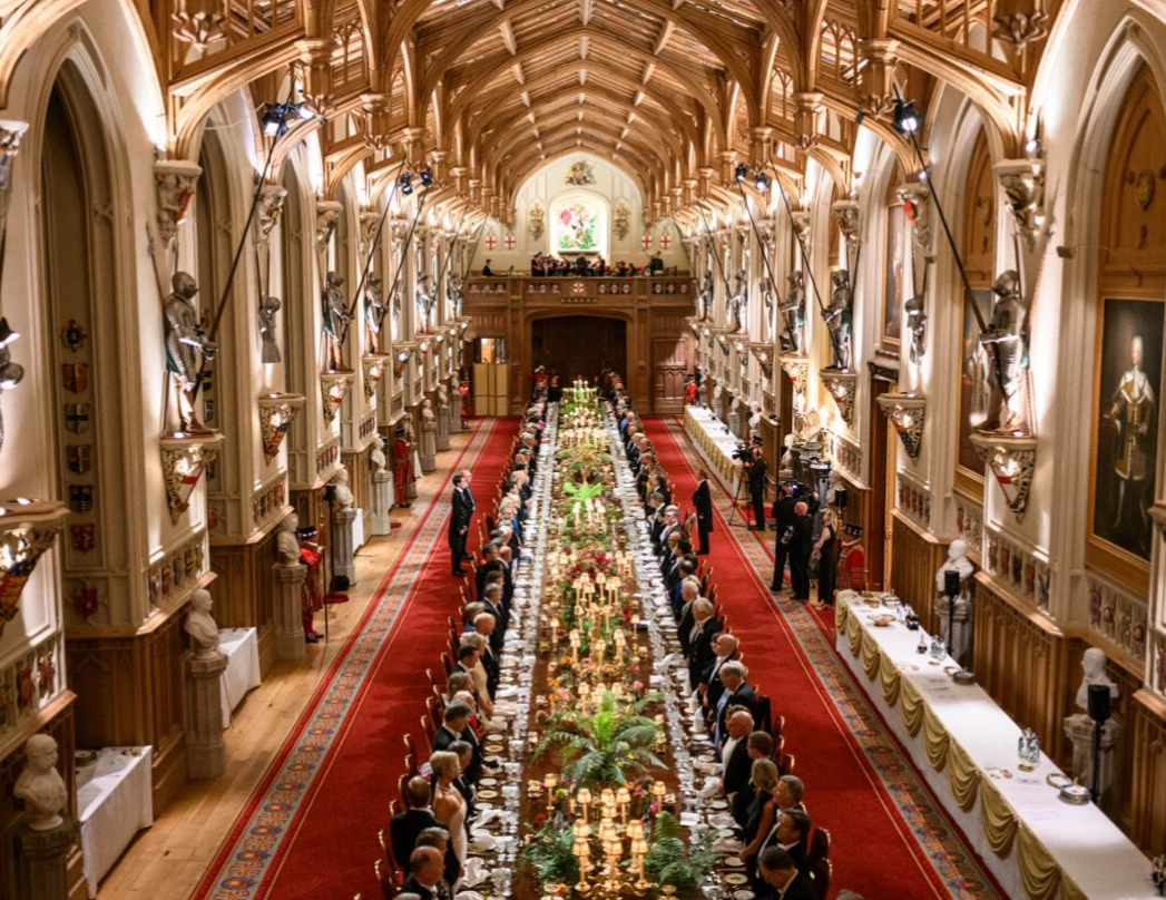 An absurdly long formal banquet table stretching down a grand hall